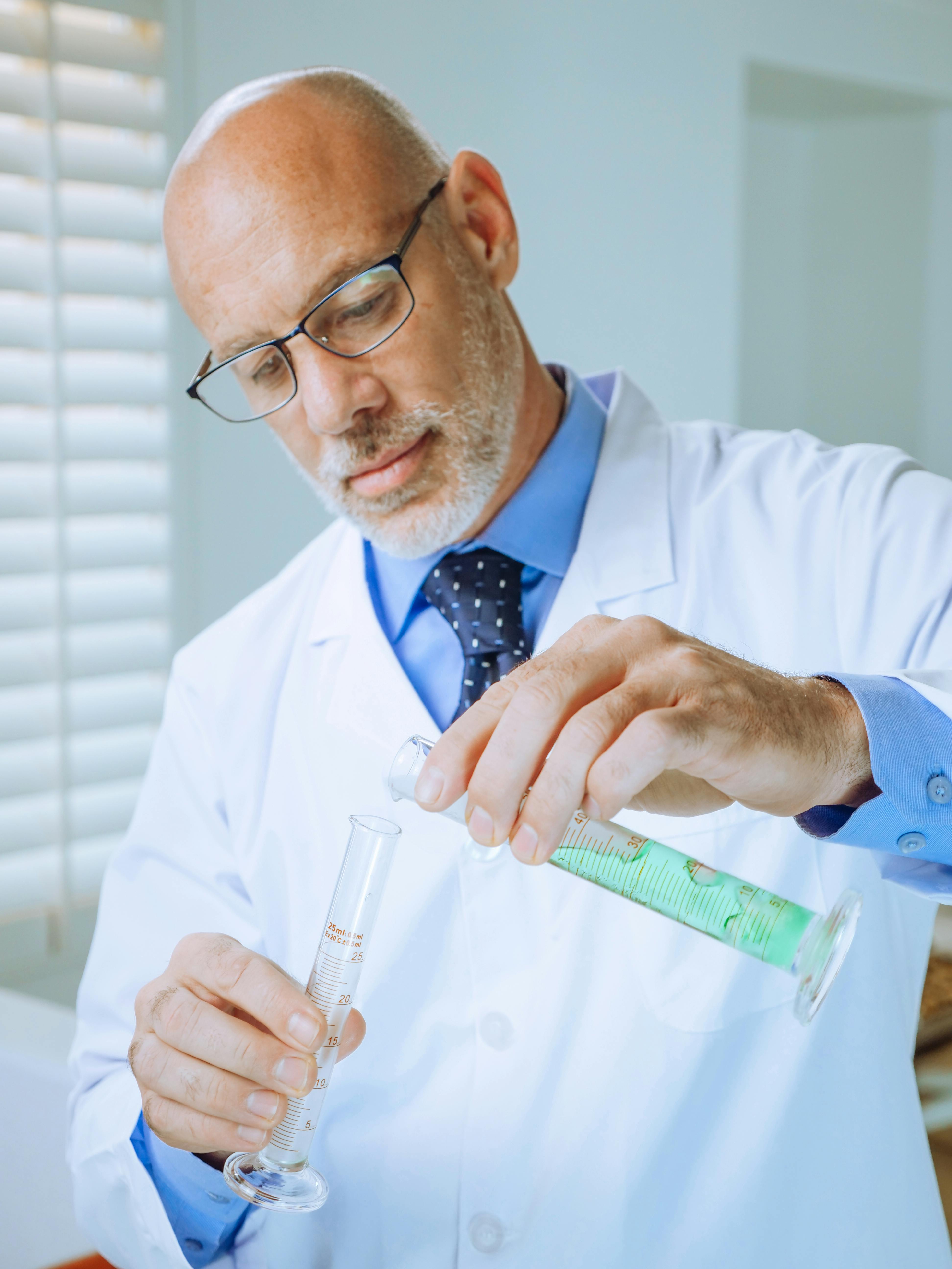 Portrait of handsome eye doctor sitting with ophthalmologic device in the cabinet